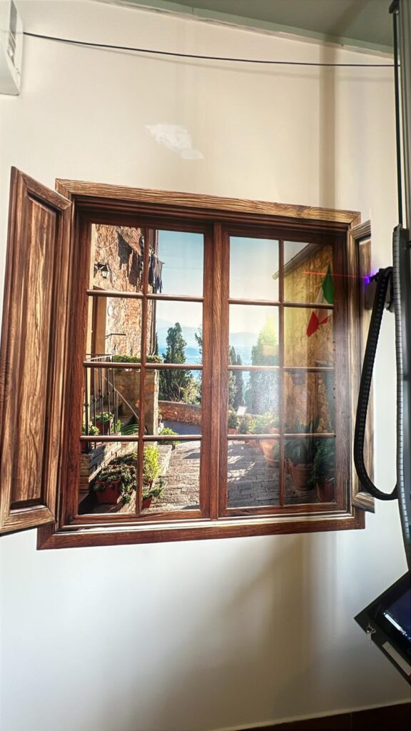 Photorealistic 3D window illusion mural depicting a Tuscan courtyard scene printed on a smooth wall.